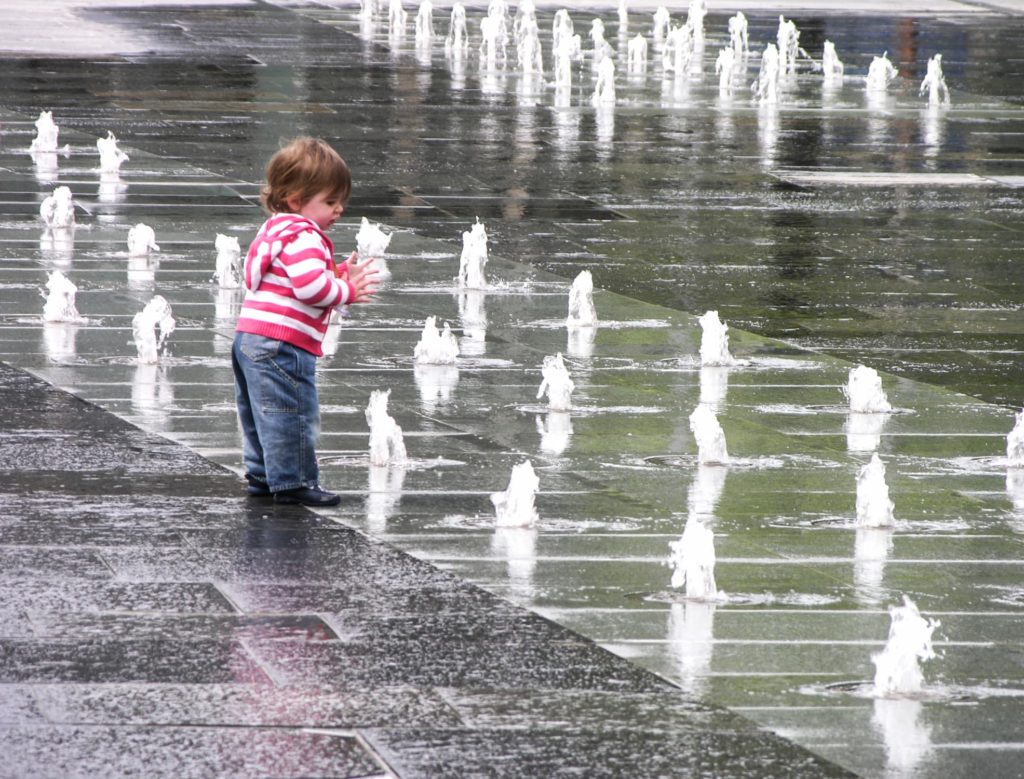 Child enjoying waterjet fountains at Custom House Square, Belfast